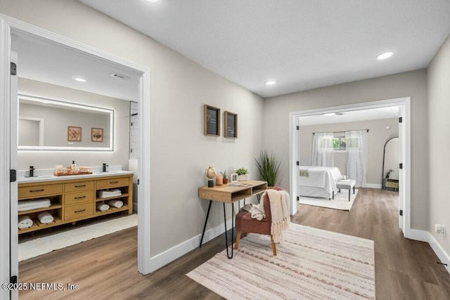 corridor with baseboards, wood finished floors, and recessed lighting