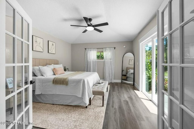 bedroom with a textured ceiling, french doors, wood finished floors, and baseboards