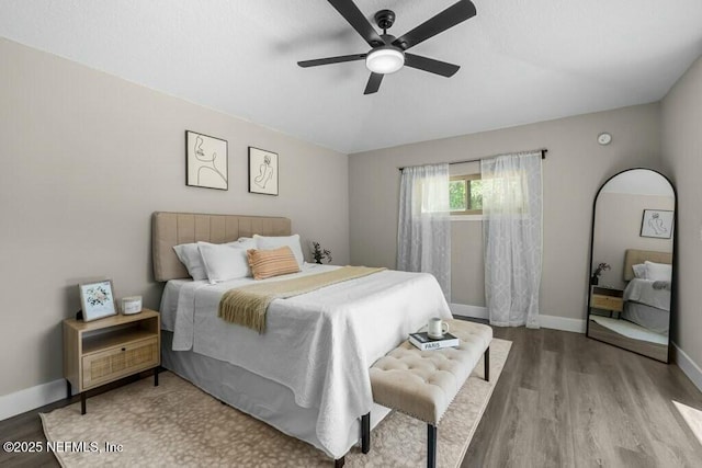 bedroom with ceiling fan, wood finished floors, and baseboards