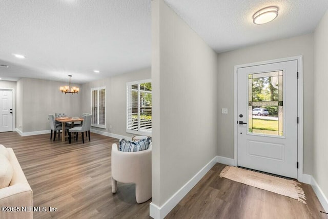 foyer entrance with plenty of natural light, a textured ceiling, and wood finished floors