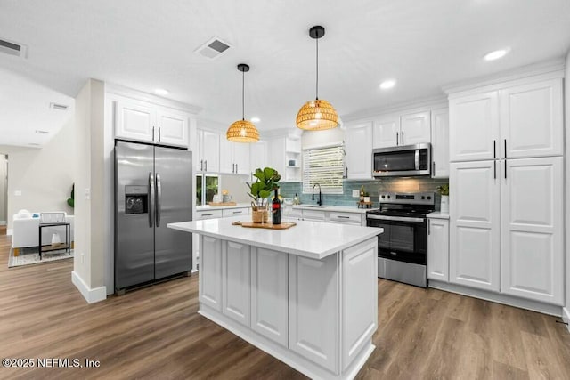 kitchen featuring visible vents, appliances with stainless steel finishes, light countertops, white cabinetry, and a sink