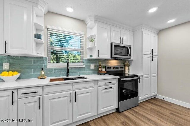 kitchen featuring a sink, stainless steel appliances, open shelves, and white cabinets