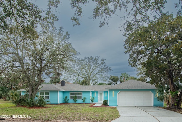 single story home featuring an attached garage, driveway, a chimney, and a front yard