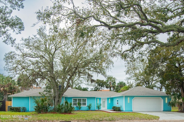 ranch-style house featuring concrete driveway, an attached garage, and a front yard