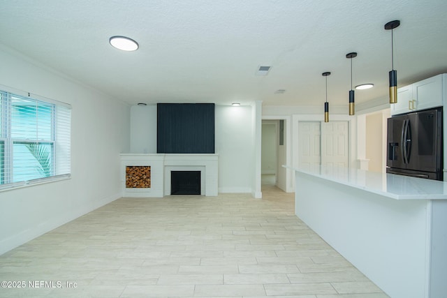 unfurnished living room featuring light wood-type flooring, visible vents, a fireplace, and a textured ceiling