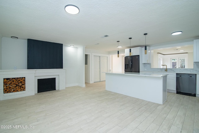 kitchen featuring dishwasher, black refrigerator with ice dispenser, light countertops, a fireplace, and a sink