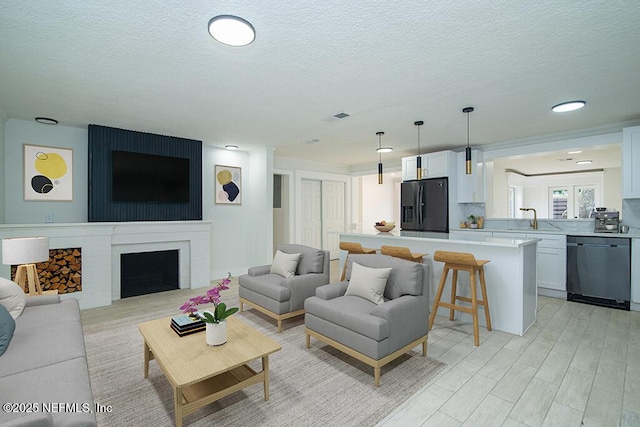 living area featuring light wood-type flooring, a fireplace, and a textured ceiling