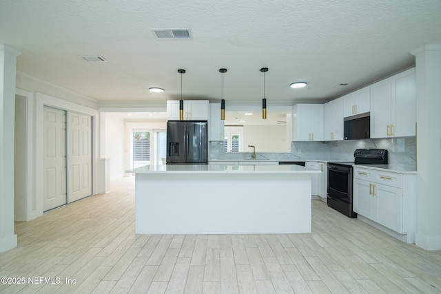 kitchen with tasteful backsplash, visible vents, light wood-style floors, light countertops, and black appliances