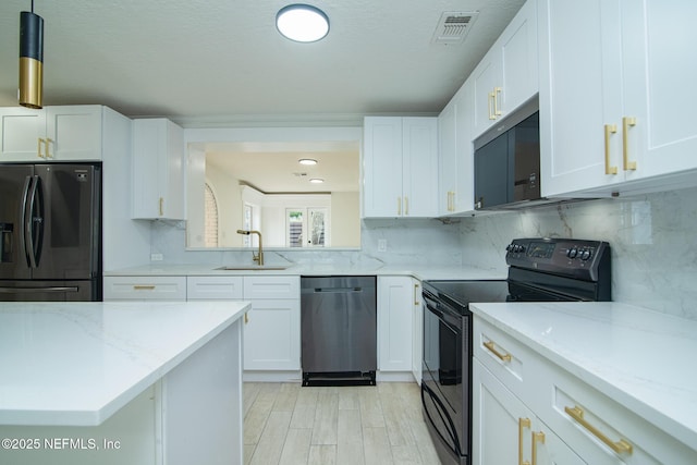 kitchen featuring visible vents, decorative backsplash, black appliances, white cabinetry, and a sink