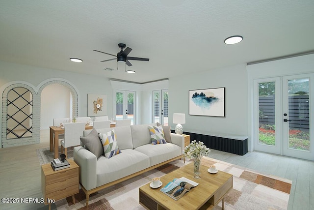 living area featuring plenty of natural light, light wood-style flooring, and french doors