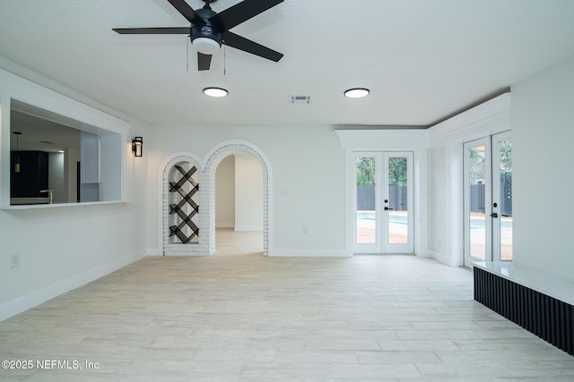 empty room with baseboards, visible vents, ceiling fan, wood finished floors, and french doors