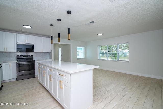 kitchen featuring white cabinets, decorative backsplash, appliances with stainless steel finishes, light countertops, and light wood-style floors