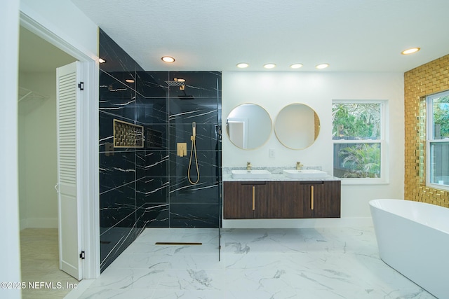 bathroom with marble finish floor, a marble finish shower, a sink, and a soaking tub