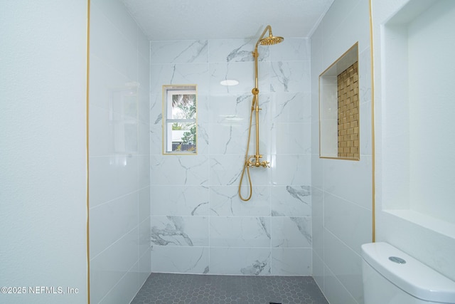 bathroom featuring tiled shower and toilet