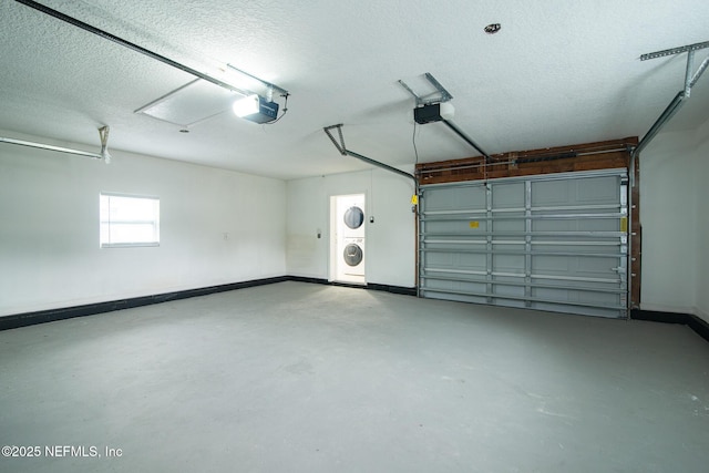 garage featuring baseboards, stacked washing maching and dryer, and a garage door opener