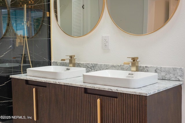 full bath with double vanity, a sink, and a shower stall