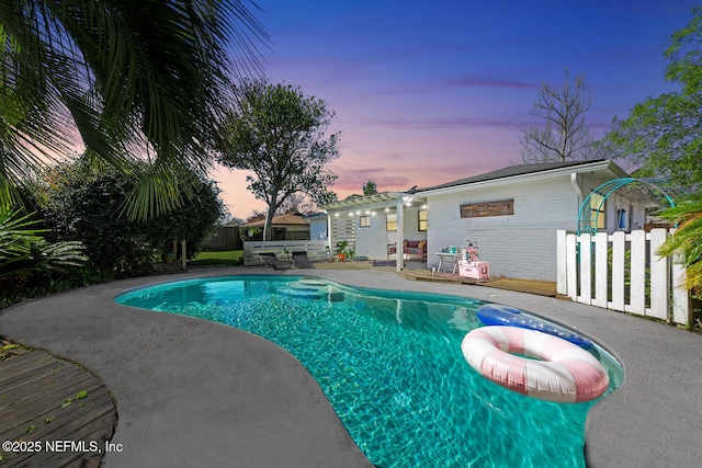 pool at dusk featuring a fenced in pool, fence, and a patio