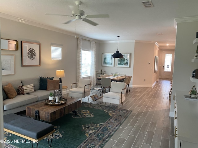 living area with ornamental molding, wood finished floors, visible vents, and a healthy amount of sunlight