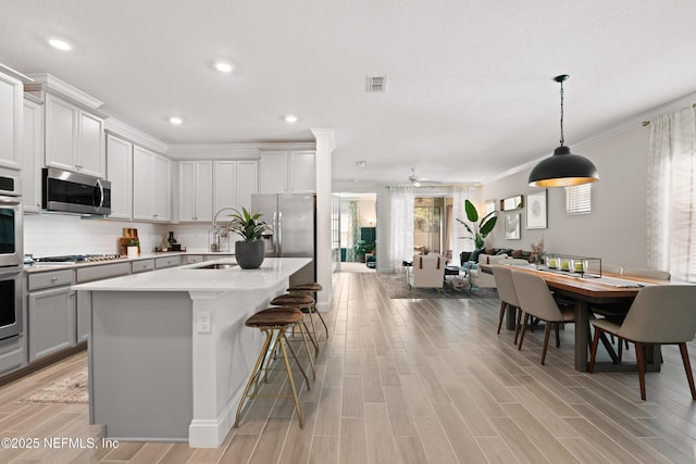 kitchen with visible vents, appliances with stainless steel finishes, open floor plan, light countertops, and backsplash