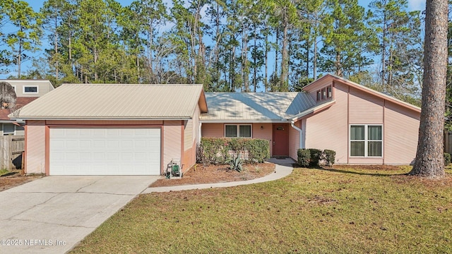 view of front of property featuring a garage, driveway, metal roof, and a front yard