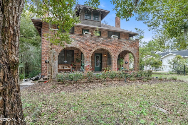 view of front of property with a chimney, fence, a porch, and brick siding