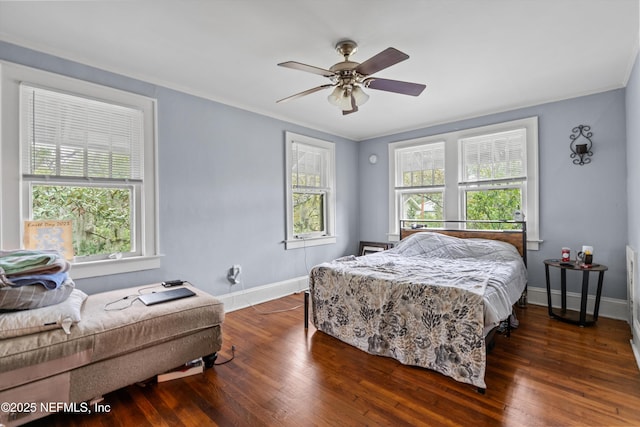 bedroom with multiple windows, wood finished floors, and baseboards