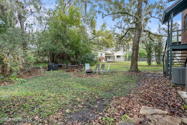 view of yard featuring a fire pit, fence, and central air condition unit