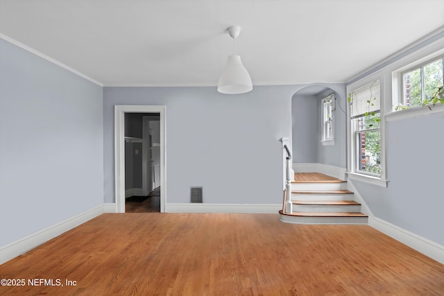 unfurnished living room featuring a healthy amount of sunlight, baseboards, stairs, and visible vents