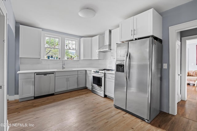 kitchen featuring wall chimney exhaust hood, appliances with stainless steel finishes, backsplash, and a sink