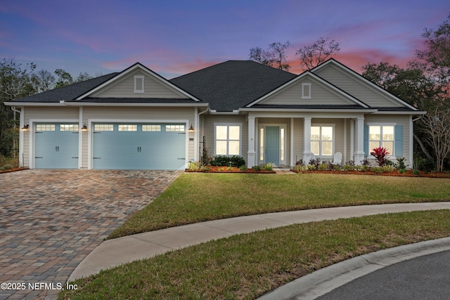 craftsman-style house with a garage, roof with shingles, decorative driveway, and a front yard