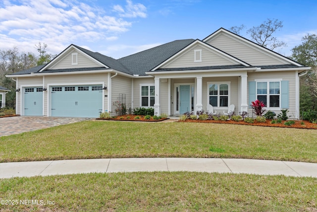 view of front of home featuring a garage, a shingled roof, a front lawn, and decorative driveway