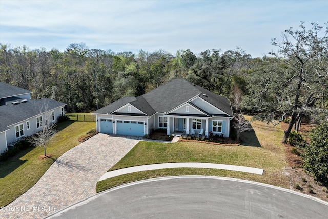 view of front of home with an attached garage, fence, decorative driveway, and a front yard