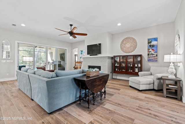 living area with recessed lighting, light wood-type flooring, visible vents, and a brick fireplace