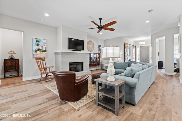 living area with light wood-style floors, a fireplace, visible vents, and recessed lighting