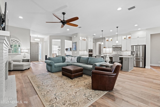 living room featuring light wood-type flooring, visible vents, a wealth of natural light, and recessed lighting