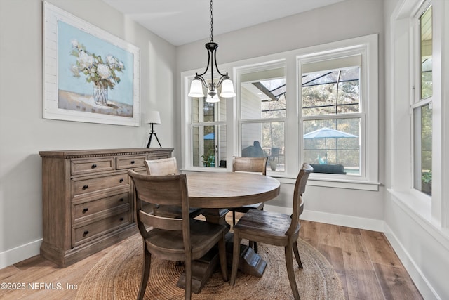 dining space featuring light wood-style floors, baseboards, and an inviting chandelier