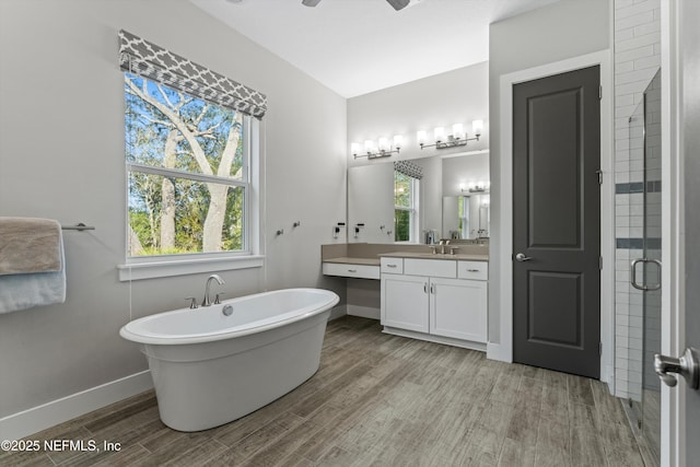 bathroom with baseboards, a soaking tub, wood finished floors, vanity, and a shower stall