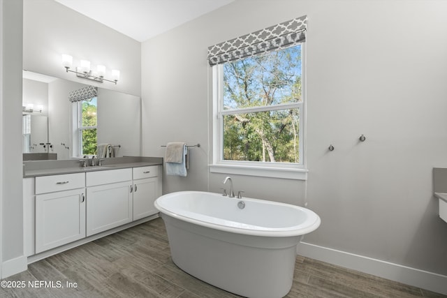 full bathroom with a soaking tub, wood finished floors, and a healthy amount of sunlight