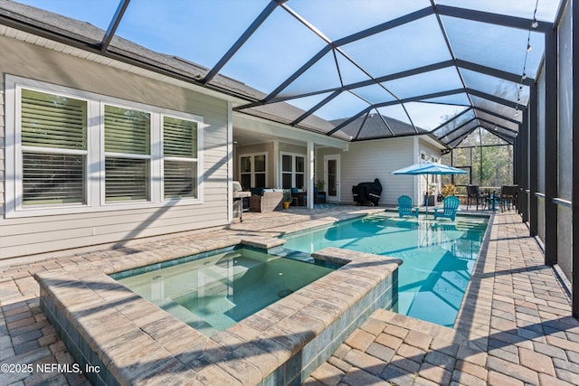 view of pool featuring a pool with connected hot tub, a patio, and a lanai