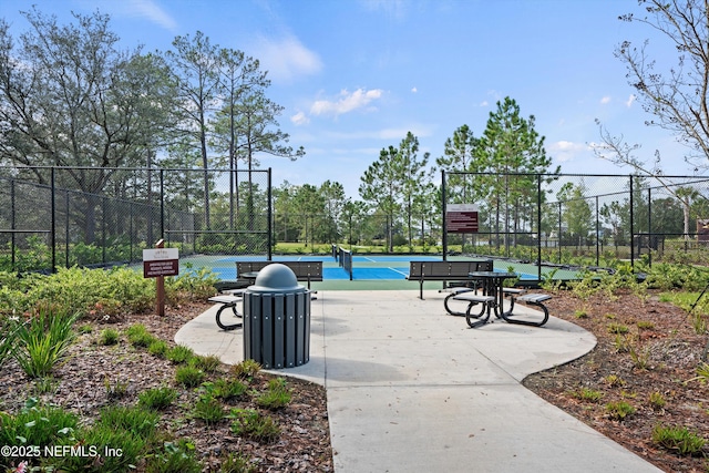 view of community with a tennis court and fence