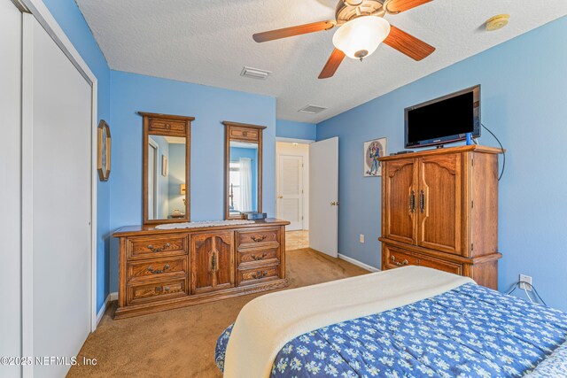 bedroom with light carpet, baseboards, visible vents, ceiling fan, and a textured ceiling