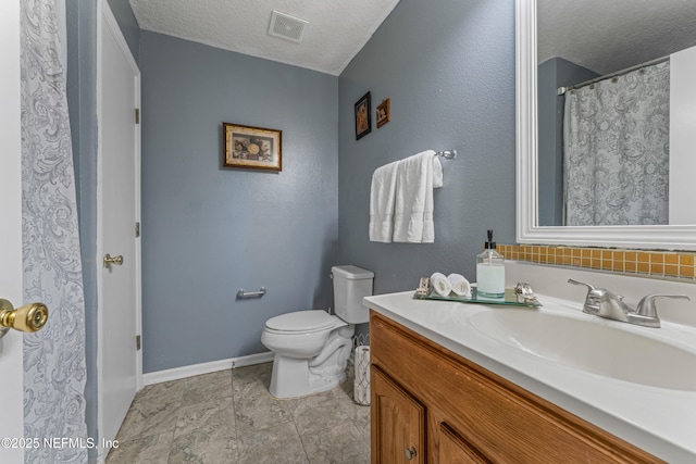 bathroom with a textured ceiling, toilet, vanity, visible vents, and baseboards