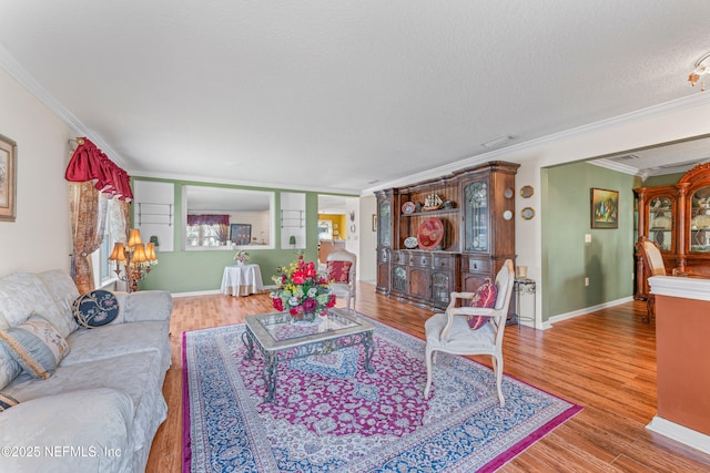 living room featuring crown molding, a textured ceiling, baseboards, and wood finished floors