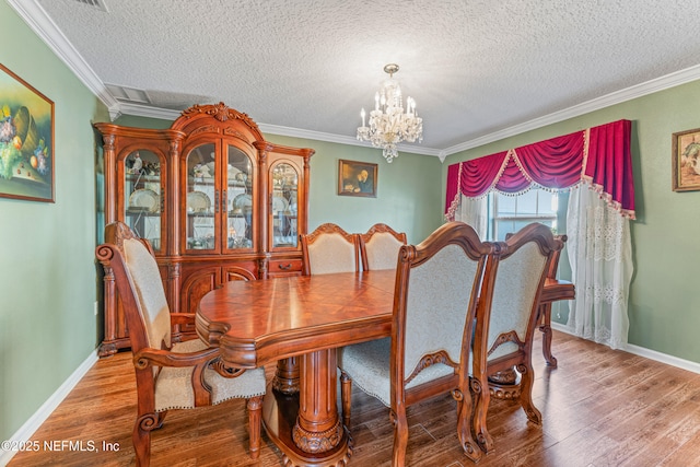 dining room with crown molding, a textured ceiling, a chandelier, and wood finished floors