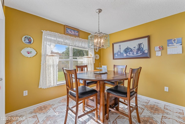 dining room featuring a textured ceiling, a notable chandelier, and baseboards