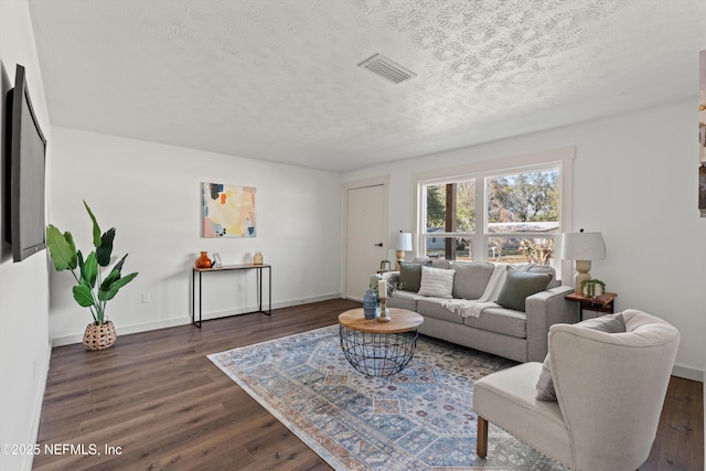 living area featuring dark wood-style flooring, visible vents, and a textured ceiling