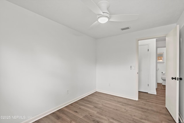 spare room featuring a ceiling fan, baseboards, visible vents, and wood finished floors