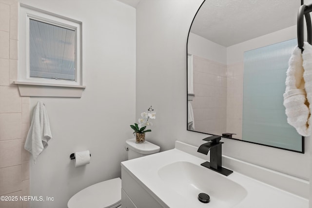 bathroom featuring toilet, a textured ceiling, and vanity