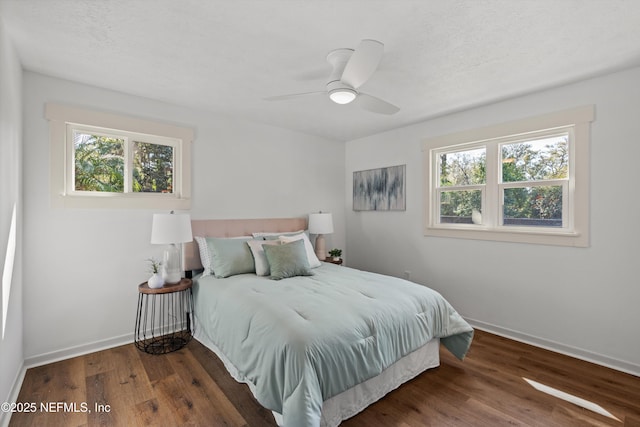 bedroom with a ceiling fan, a textured ceiling, baseboards, and wood finished floors