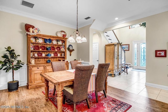 dining area featuring light wood finished floors, ornamental molding, stairs, and visible vents